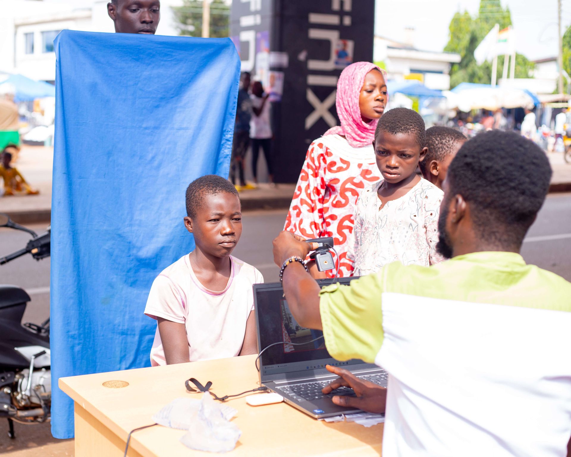 AdvoCare volunteer registering a child for NHIS at an outdoor desk